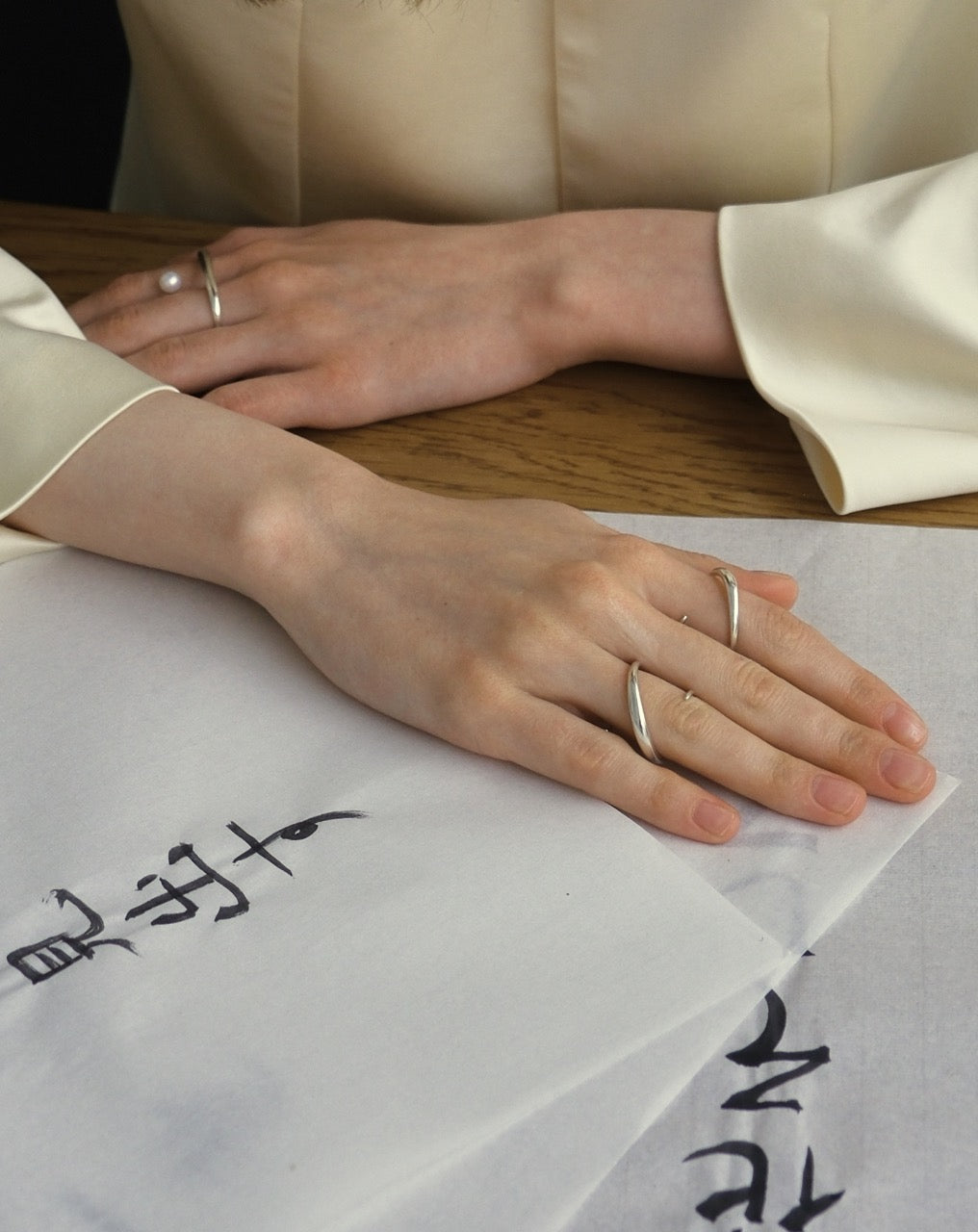 Kaisho silver ring styled on Japanese calligraphy desk, hands flat on script paper