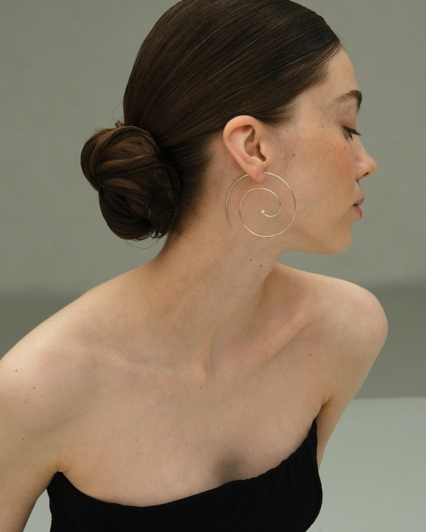 Editorial profile of model with low bun in strapless black top wearing Lera Treyger Reisho silver pearl spiral hoop
