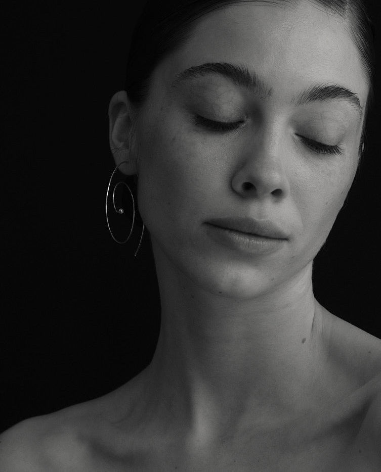 Black-and-white portrait of model with closed eyes wearing Lera Treyger Reisho silver pearl spiral hoop earring