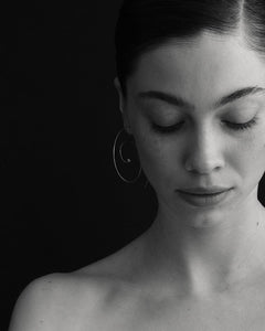 B&W portrait of model with slick hair looking downward wearing Lera Treyger Reisho silver spiral pearl hoop earring