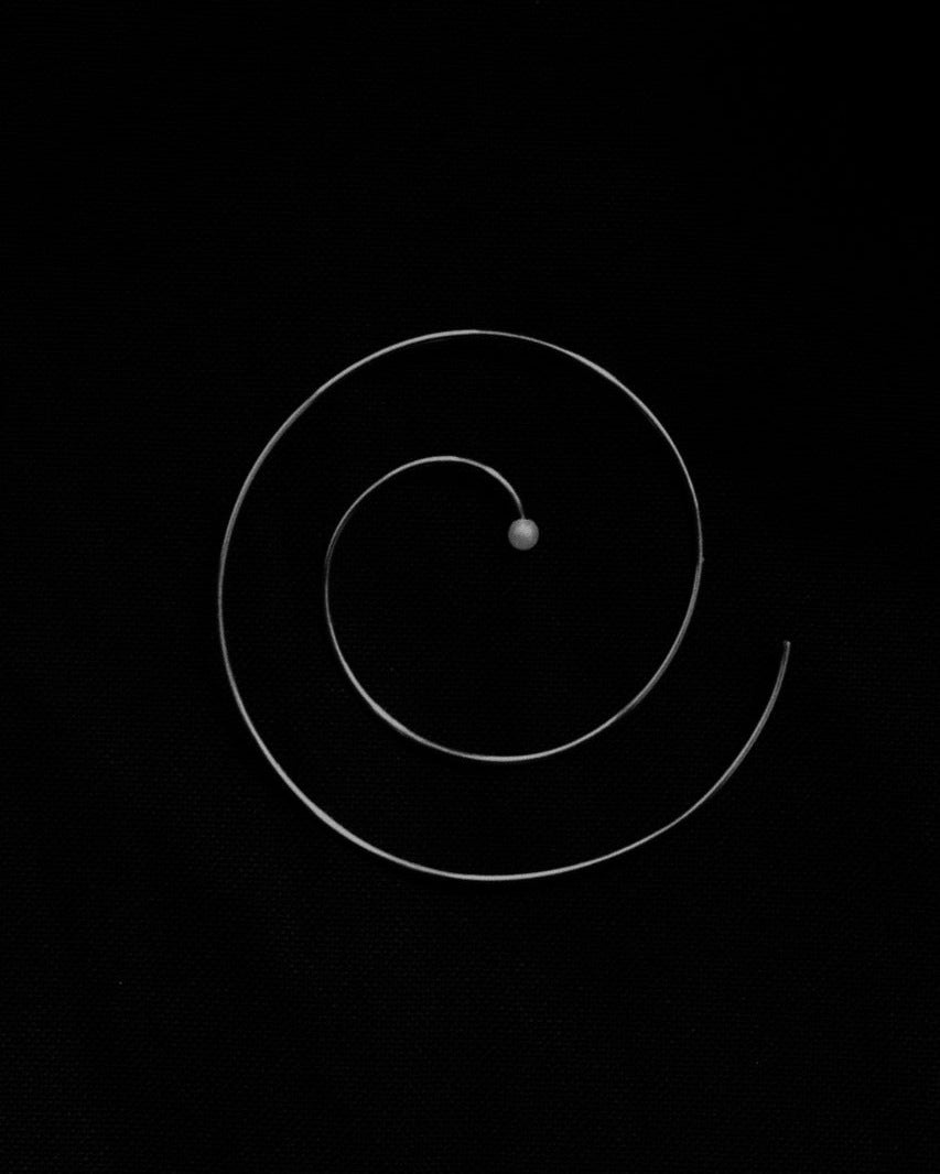 Atmospheric B&W still life of Lera Treyger Reisho sterling silver spiral hoop earring with central pearl on black
