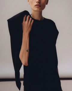 Model in black structured top wearing Lera Treyger Ukiyo n 3 white gold diamond tennis bracelet with emerald drop
