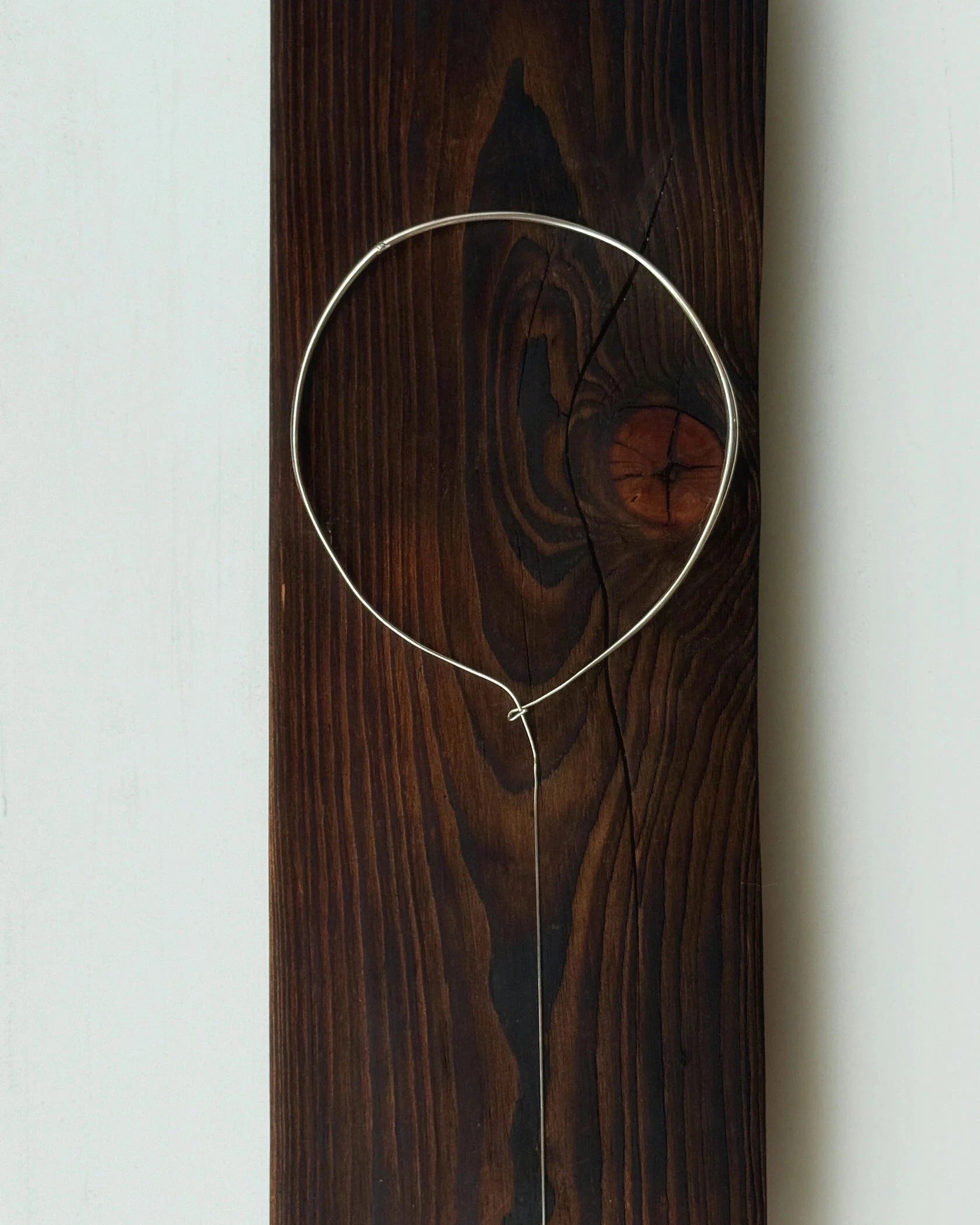 Lera Treyger x Anouk Yve silver collar styled on a dark stained wood plank, atmospheric still life