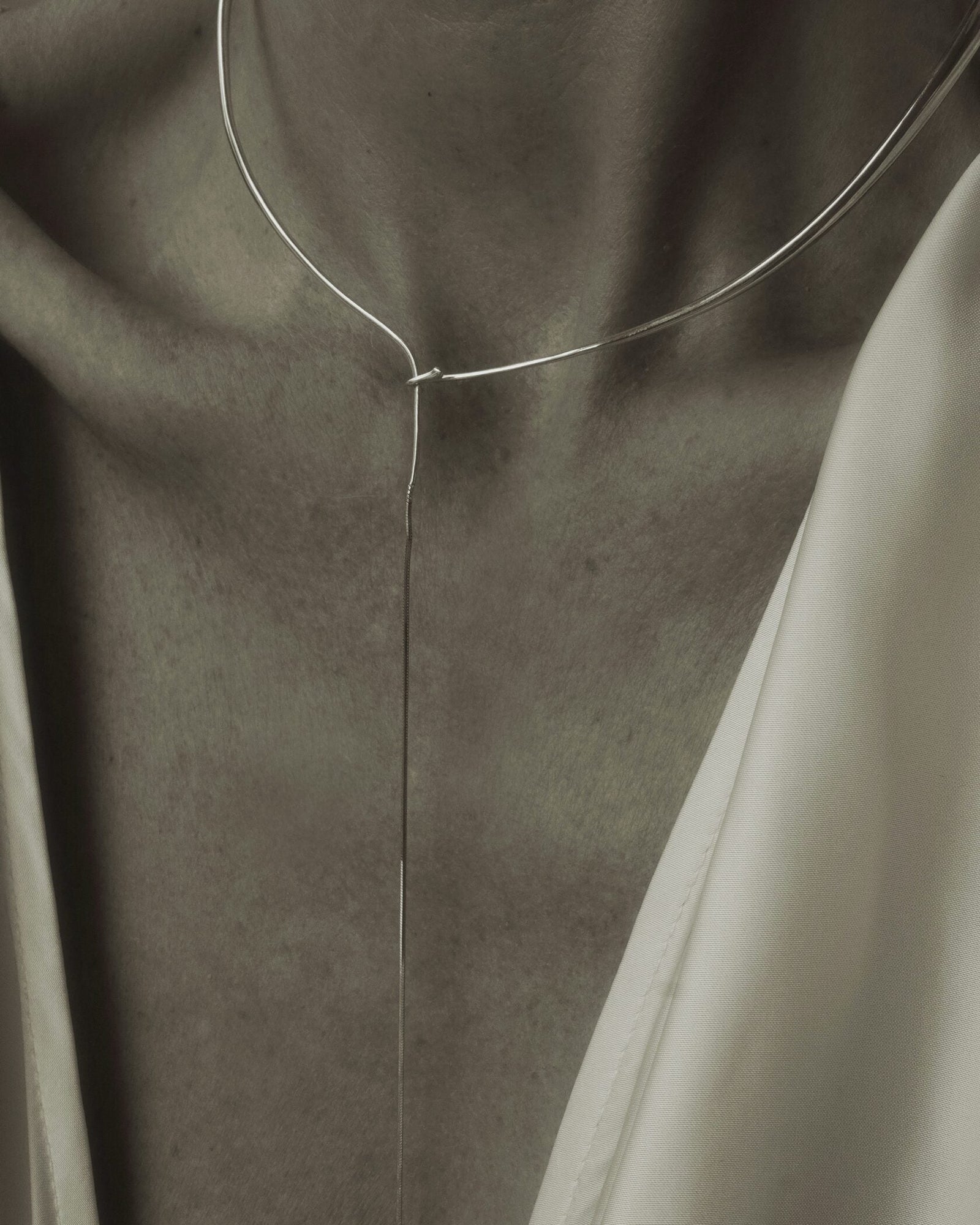 Color editorial of model's décolletage wearing Lera Treyger x Anouk Yve silver collar against beige silk top