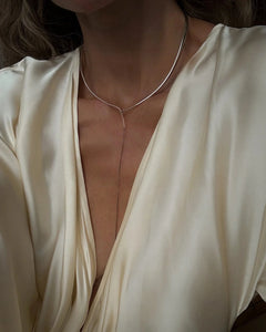 Close-up of model's chest in cream silk plunge top with Lera Treyger x Anouk Yve silver collar and lariat chain