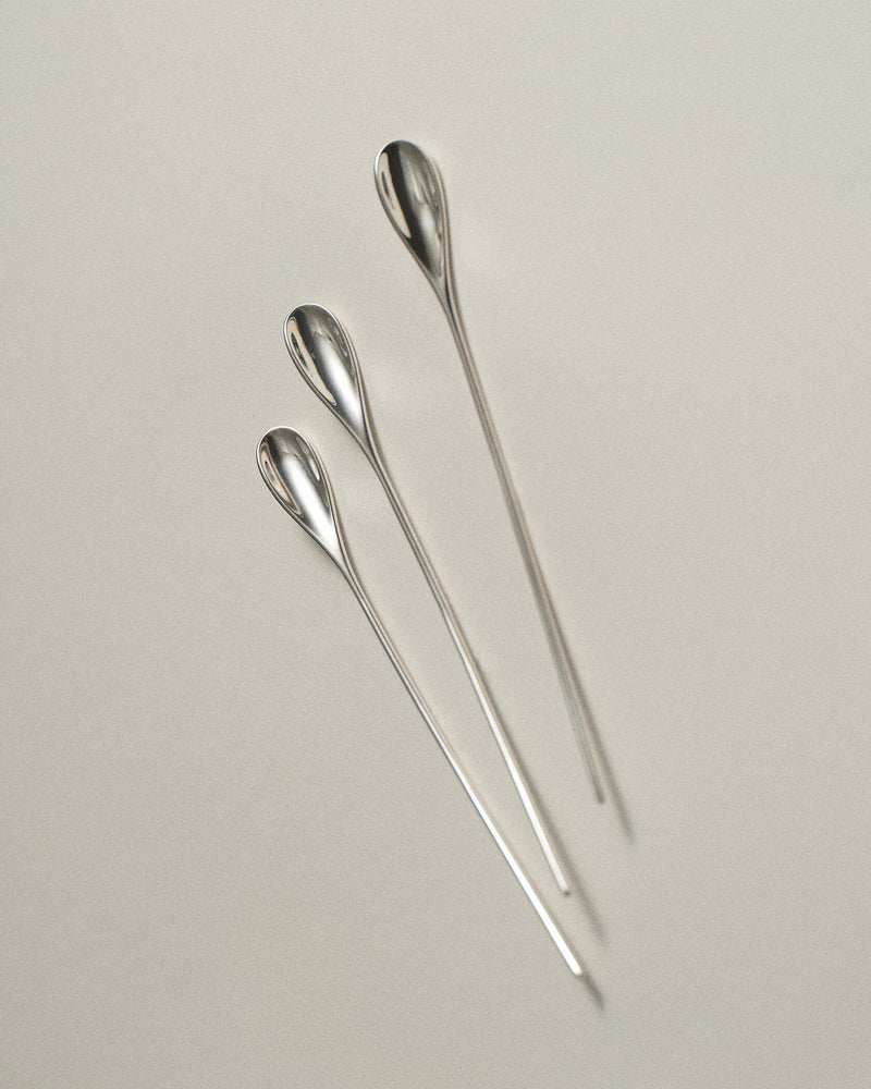 Three Lera Treyger LOBBY sterling silver coffee spoons arranged in diagonal formation on warm cream paper, editorial