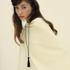 Editorial portrait of model with brushed hair and ivory wool top wearing Lera Treyger Dai sterling silver bar pendant with black tassel