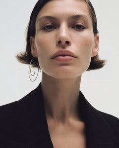Editorial of model with short brunette bob in black blazer wearing single Lera Treyger Reisho 14k gold pearl spiral hoop