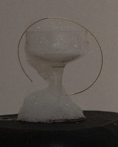 Top-down lifestyle of Lera Treyger Earth gold diamond choker arranged around a foamy champagne coupe