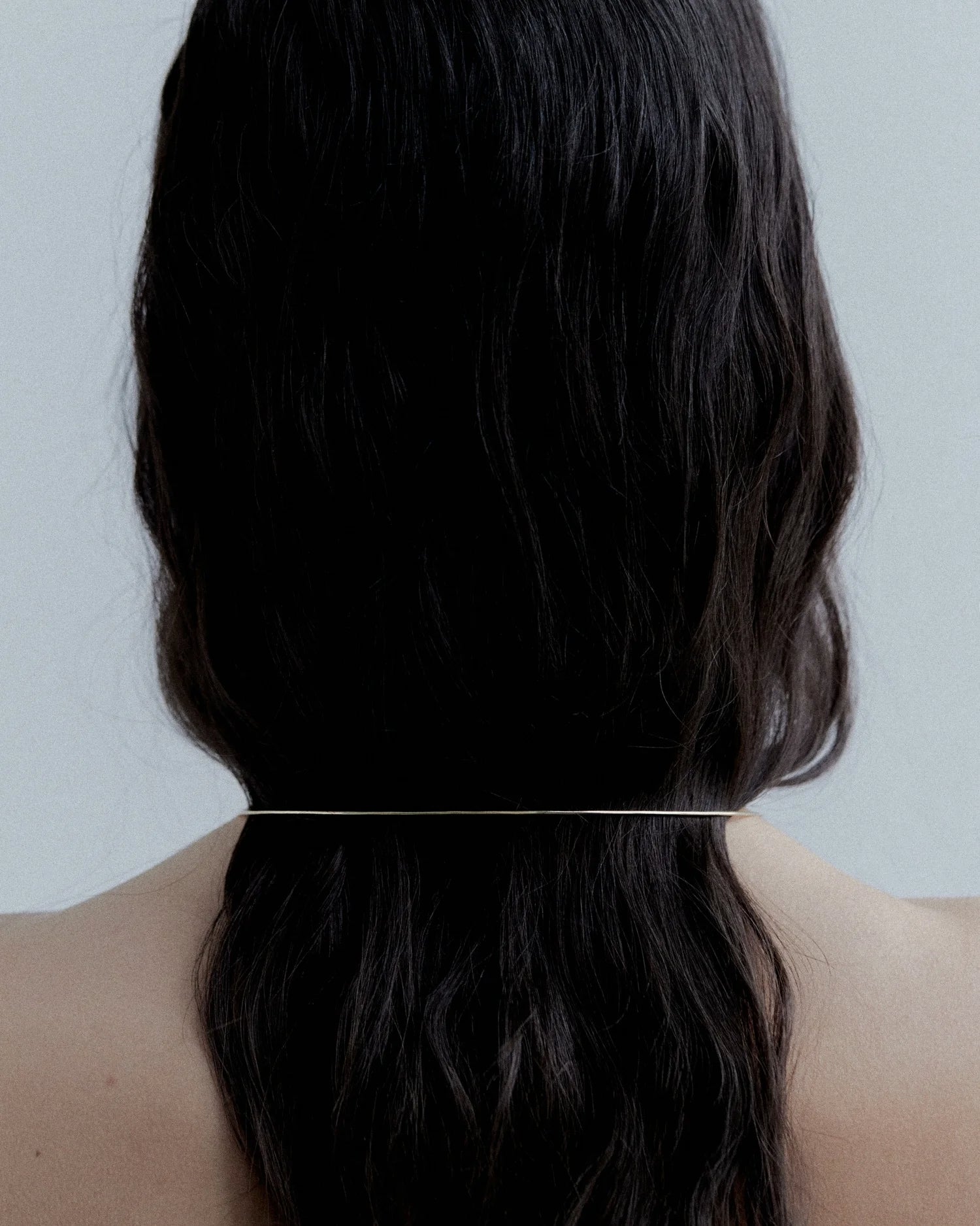 B&W back-of-head shot of model with dark waves showing Lera Treyger Earth gold choker rim at the nape