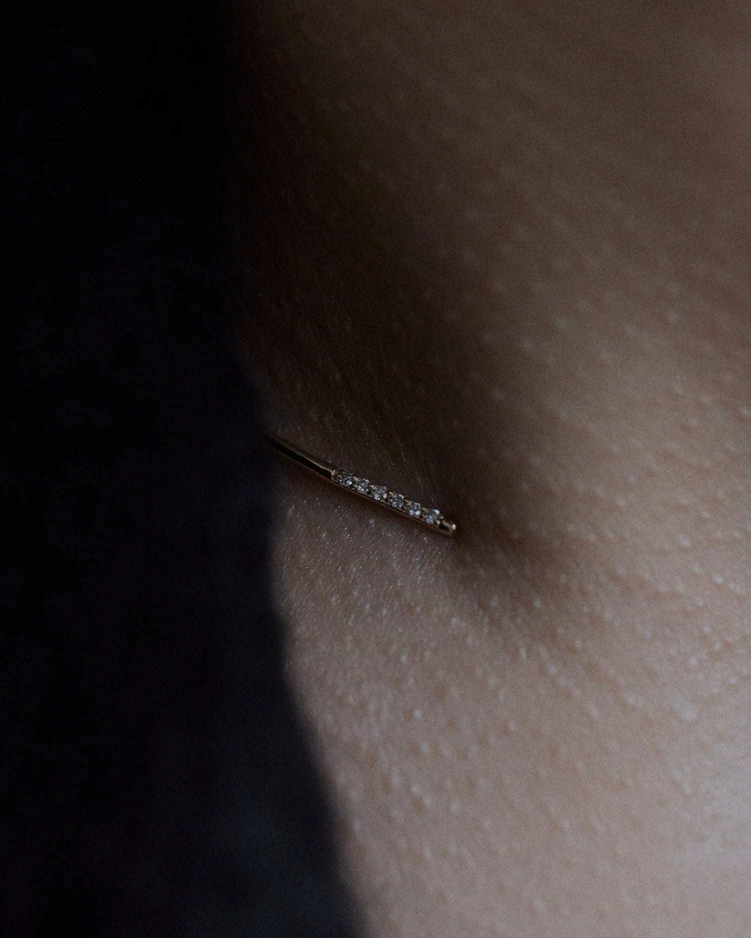 Macro of Lera Treyger Earth 14k gold choker tip with row of pavé diamonds resting on warm skin