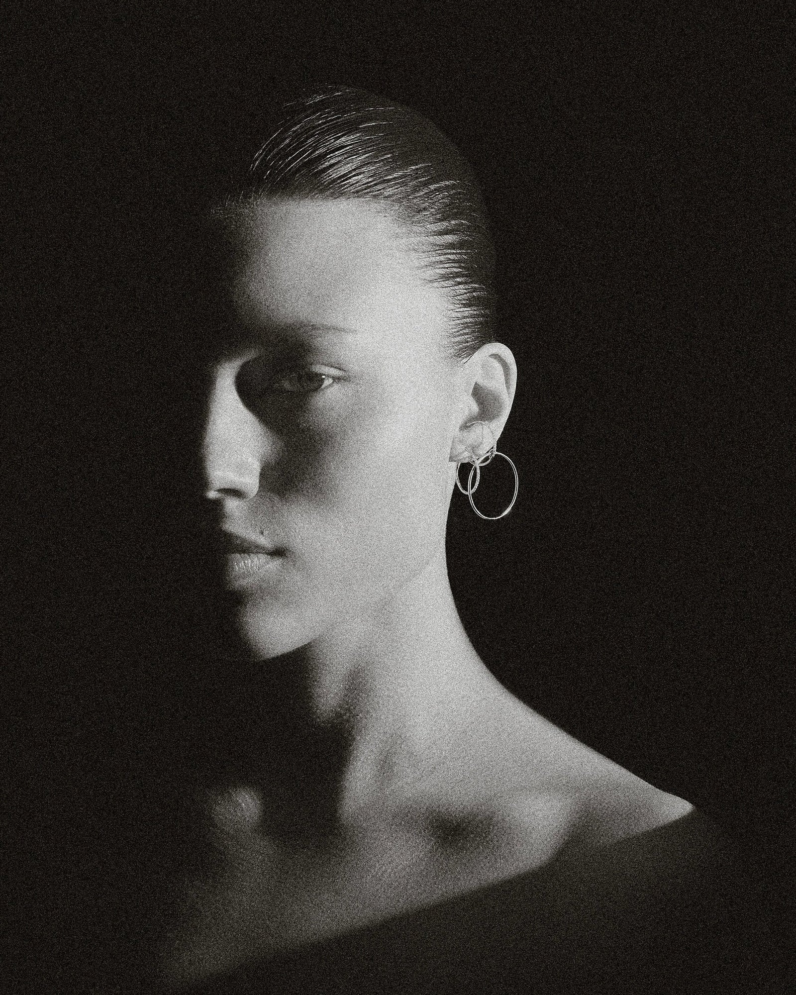 Moody B&W portrait of model with slick hair wearing pair of Lera Treyger Earth-S silver pavé-diamond small hoops