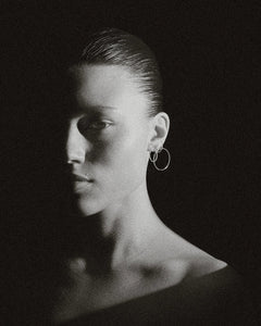 Moody B&W portrait of model with slick hair wearing pair of Lera Treyger Earth-S silver pavé-diamond small hoops