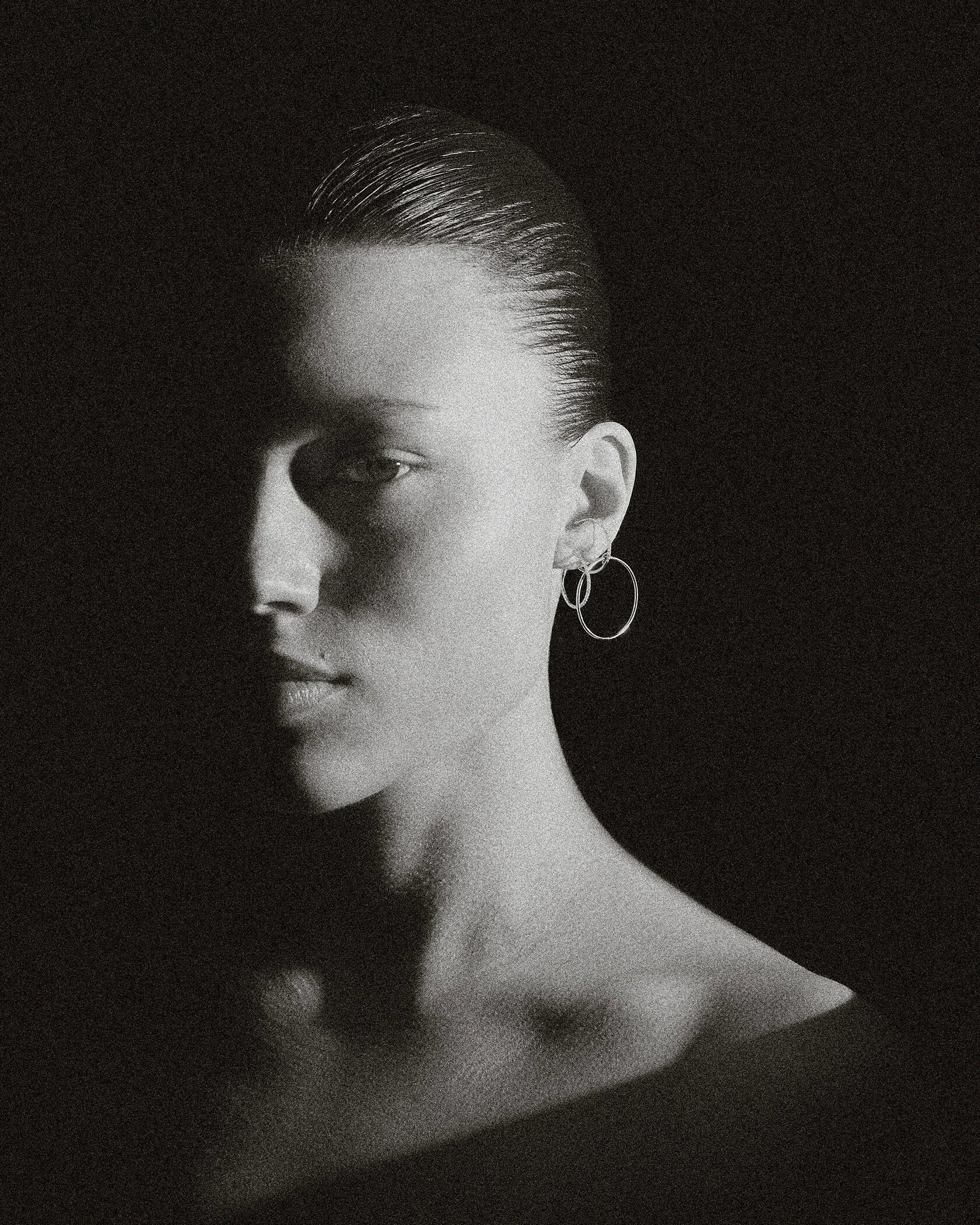 Moody B&W portrait of model with slick hair wearing pair of Lera Treyger Earth-S silver pavé-diamond small hoops
