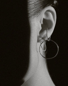 B&W detail of large diamond hoops layered with Lera Treyger Earth-S small silver pavé hoop on model's lobe