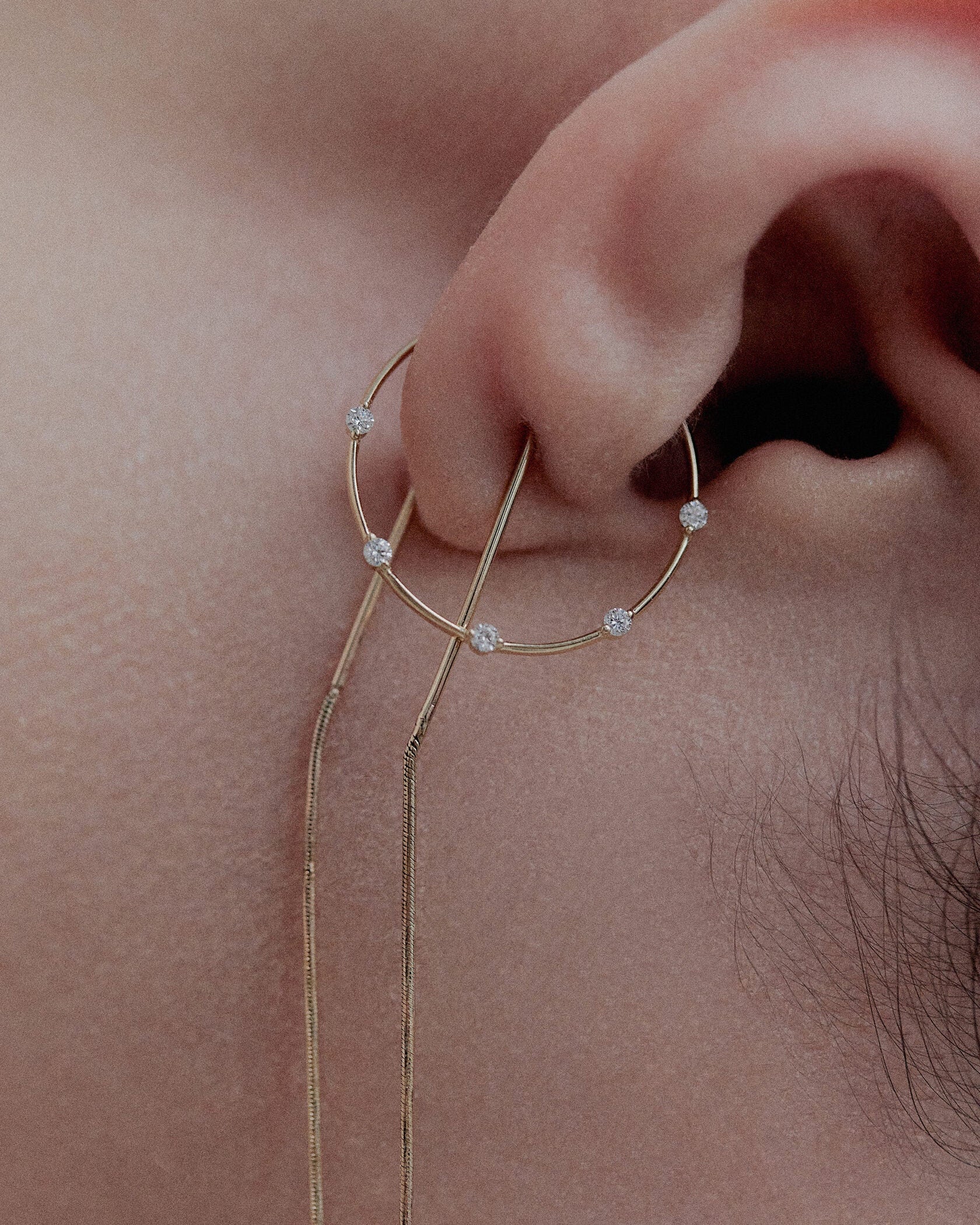Color macro of model's ear with Lera Treyger Fire 14k gold diamond cuff and two threader earrings paired together