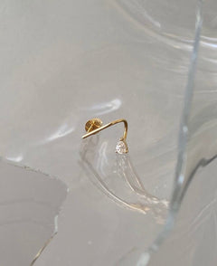 Single Lera Treyger MA 1 14k gold pear-cut diamond stud earring on shattered glass surface, daylight refraction