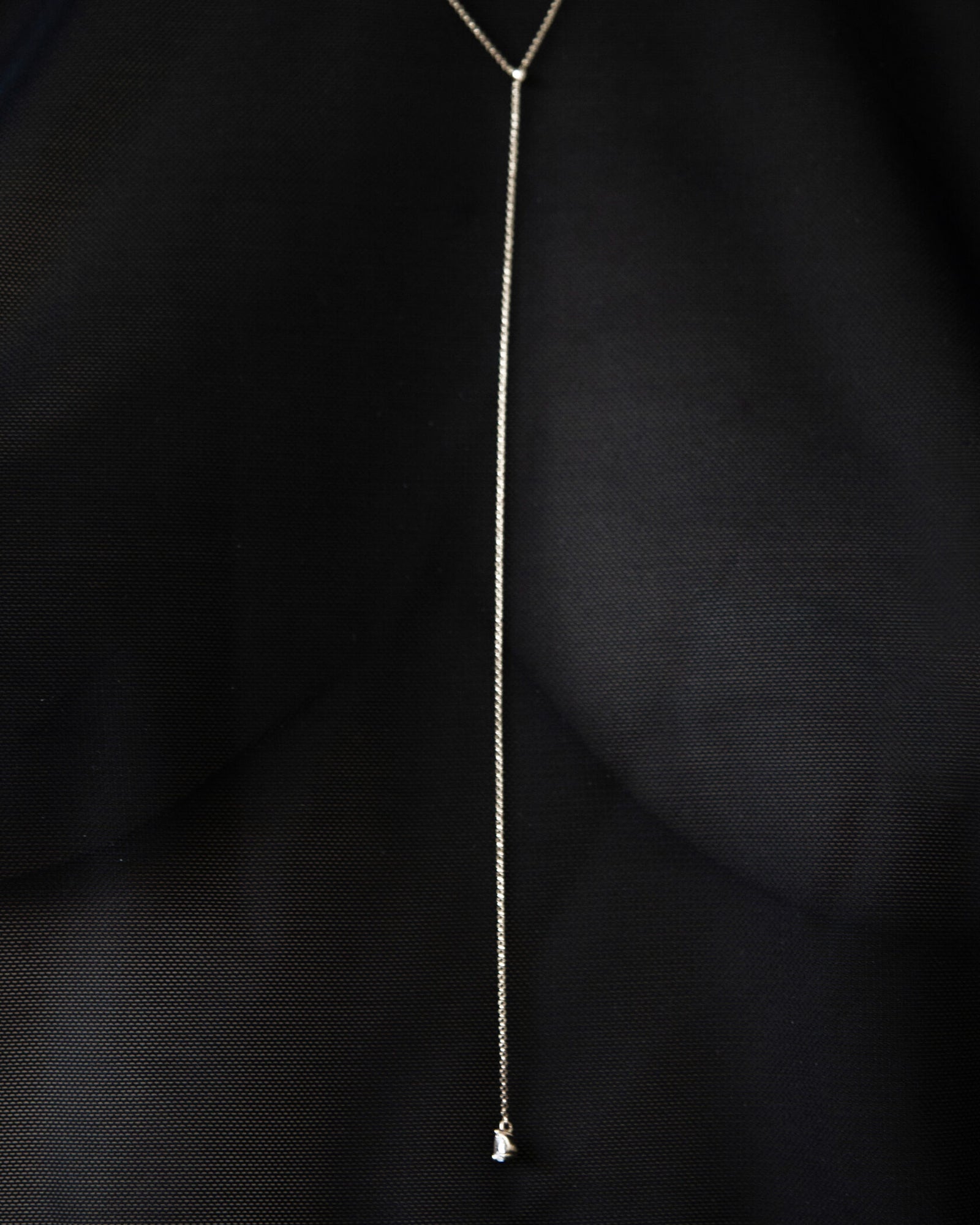 Color editorial of model in black silk wearing Lera Treyger MA 9 silver lariat with pear-diamond drop in V-neck