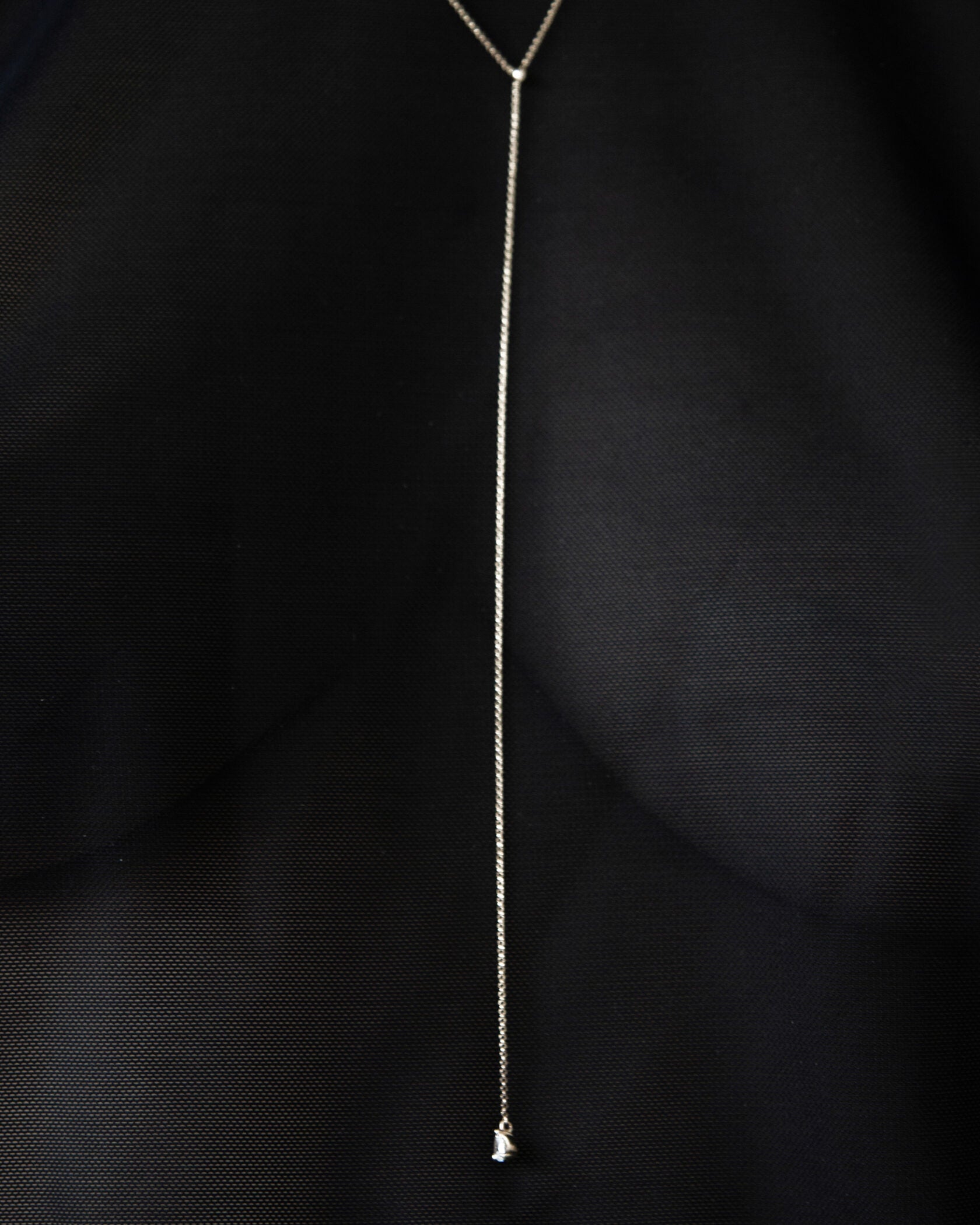 Color editorial of model in black silk wearing Lera Treyger MA 9 silver lariat with pear-diamond drop in V-neck