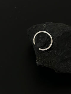 Atmospheric still life of N 14 diamond pavé ring on dark stone against black background