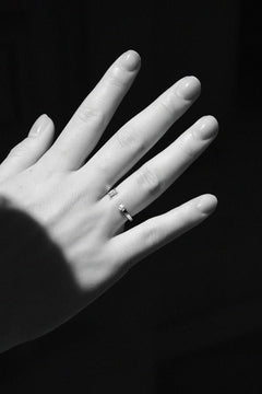 Black and white close-up of N 15 two-stone diamond ring on model's hand against dark background