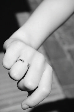 Detail of N 15 two-stone gold ring on closed fist, black and white moody composition