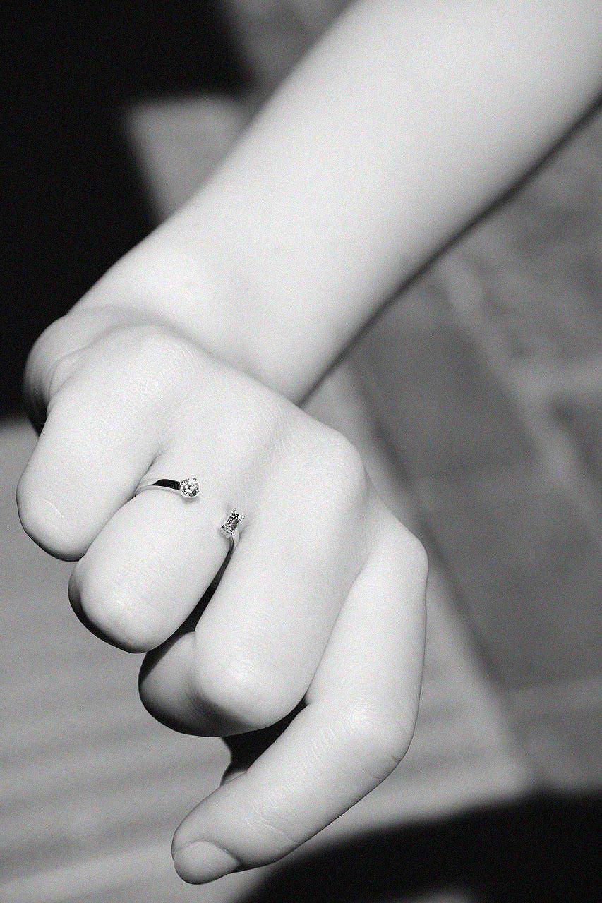 Detail of N 15 two-stone gold ring on closed fist, black and white moody composition