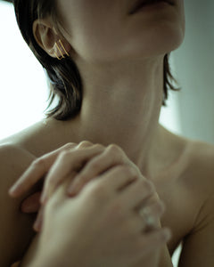 Editorial of model with hands clasped at shoulder wearing N 19 yellow gold double ear cuff