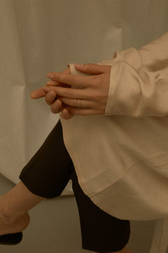 N 6 yellow gold chain ring on hand resting in lap, model in cream silk blouse and black trousers