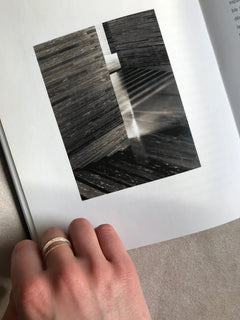 Detail of N 6 gold chain ring stacked on hand placed on photography book
