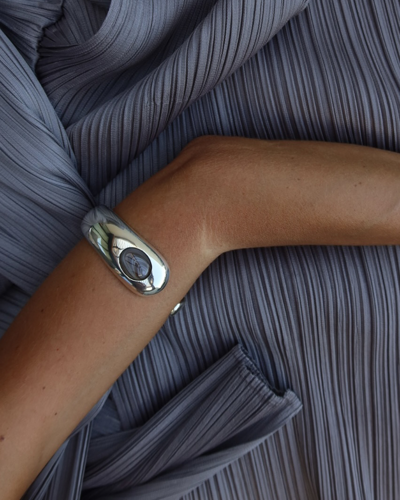 Detail of LT x O.RIM sculptural sterling silver cuff worn on a model arm against draped gray fabric
