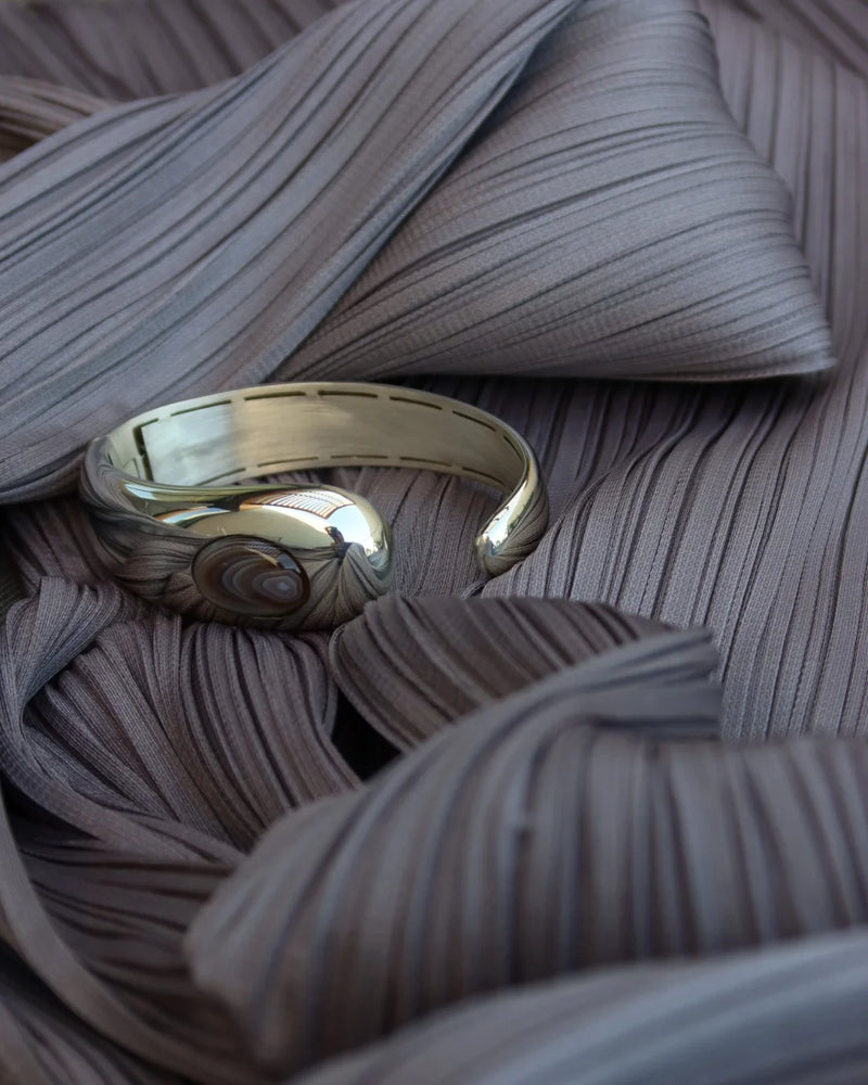 LT x O.RIM cuff bracelet in yellow gold, organic sculptural form with natural agate stone, pleated fabric backdrop