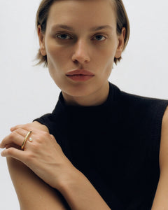 Editorial portrait of model in black sleeveless top wearing gold Sosho ring on hand at shoulder