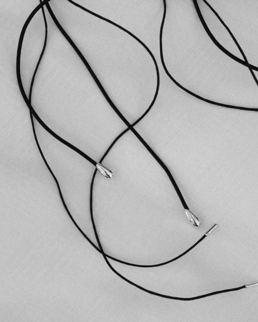 Sterling silver tip endings of the LT x O.RIM thin leather cord necklace, top-down detail shot