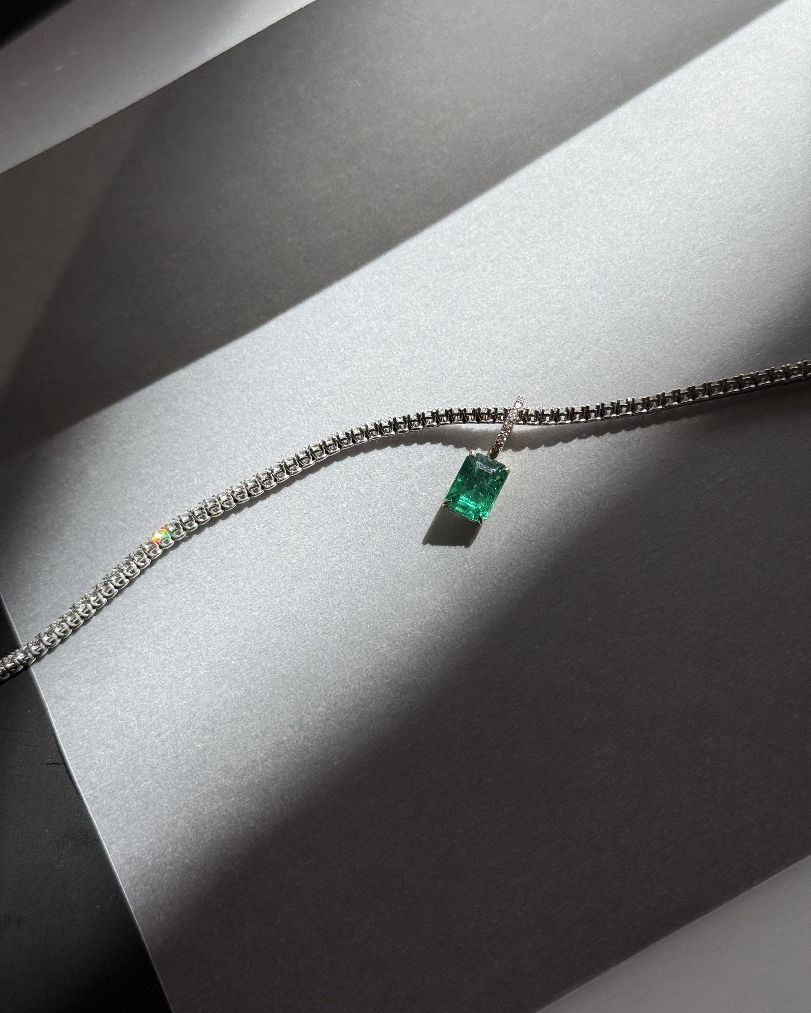 Lera Treyger Ukiyo n 3 white gold diamond tennis bracelet with emerald-cut emerald, dramatic light still life on silver paper